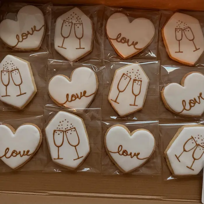 Anniversary cookies reading "love" with champagne glass designs, individually bagged