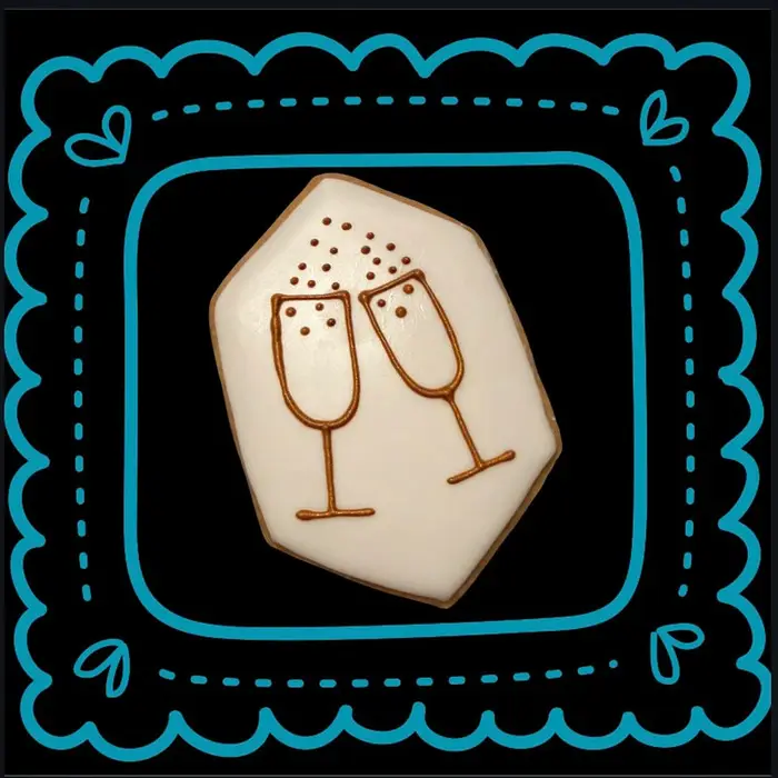A cookie decorated with two clinking champagne glasses