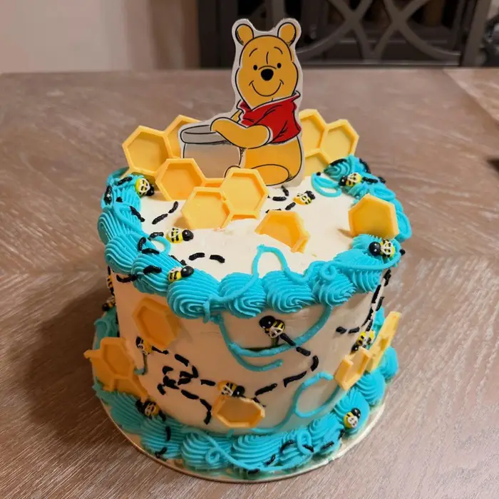 Winnie the Pooh cake in blue and yellow with honeycomb and bee details