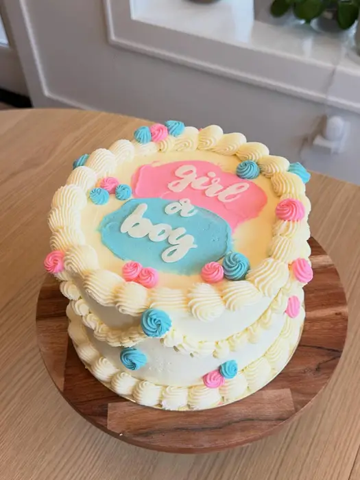 Gender reveal cake iced with "girl or boy" in pink and blue