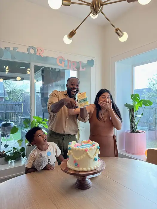 A family cutting into their gender reveal cake together at home