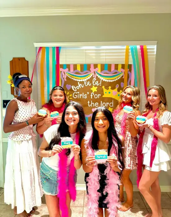 Five guests holding decorated cookies in front of the "Girls' for the lord" backdrop