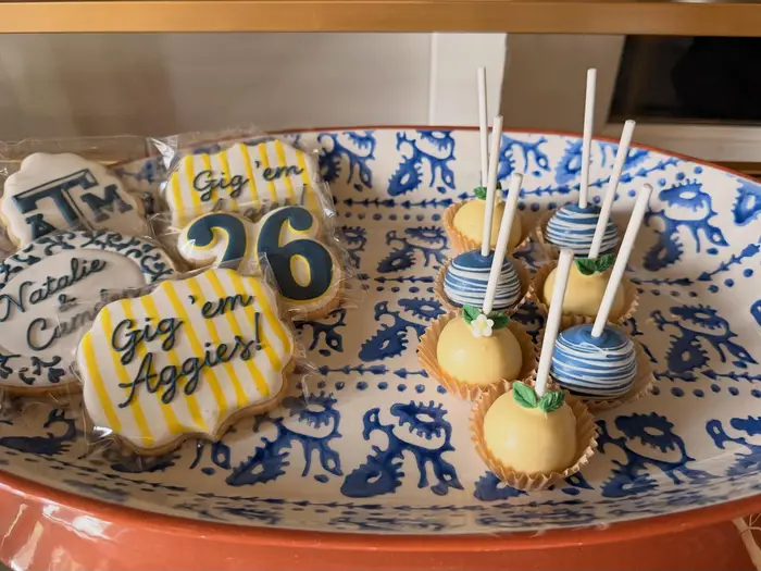 Aggies cookies and cake pops arranged on a blue patterned platter