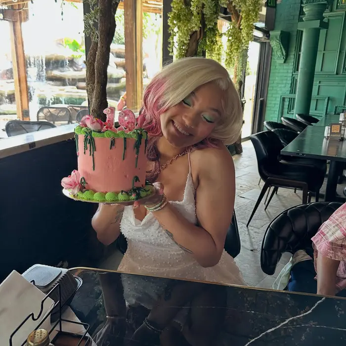 A guest smiling as she holds her pink drip birthday cake