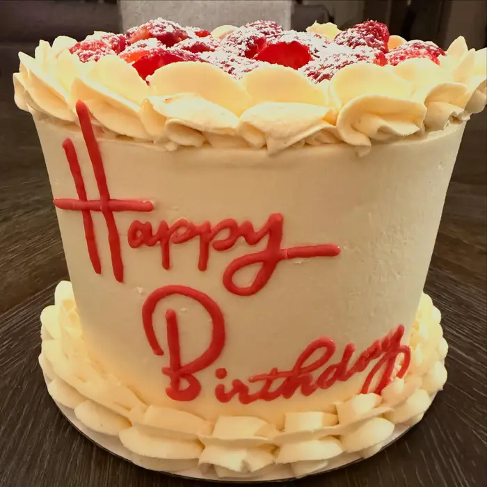 Strawberry topped vanilla cake iced with Happy Birthday in red