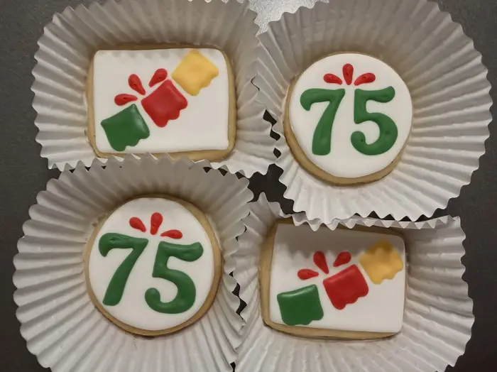 Four 75th birthday cookies in paper cases