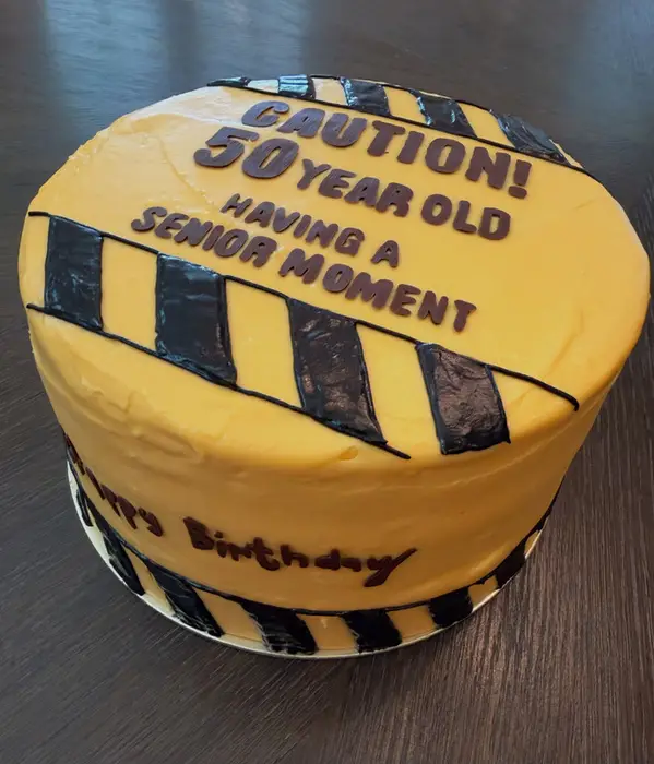 The caution tape 50th birthday cake on a dark table
