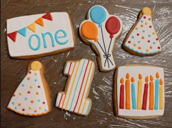 First birthday cookies with balloons, a party hat, a number one and a candle cookie